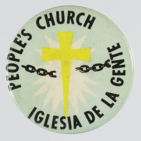 A pinback button for the People's Church / Iglesia De La Gente. The background of the button is light blue. At center there is a yellow cross with white accent behind it. A black chain is on either side of the cross. Black text around the top reads [People's Church]. black text around the bottom reads [Iglesias De La Gente]. The back of the button has a metal pin with a clasp.